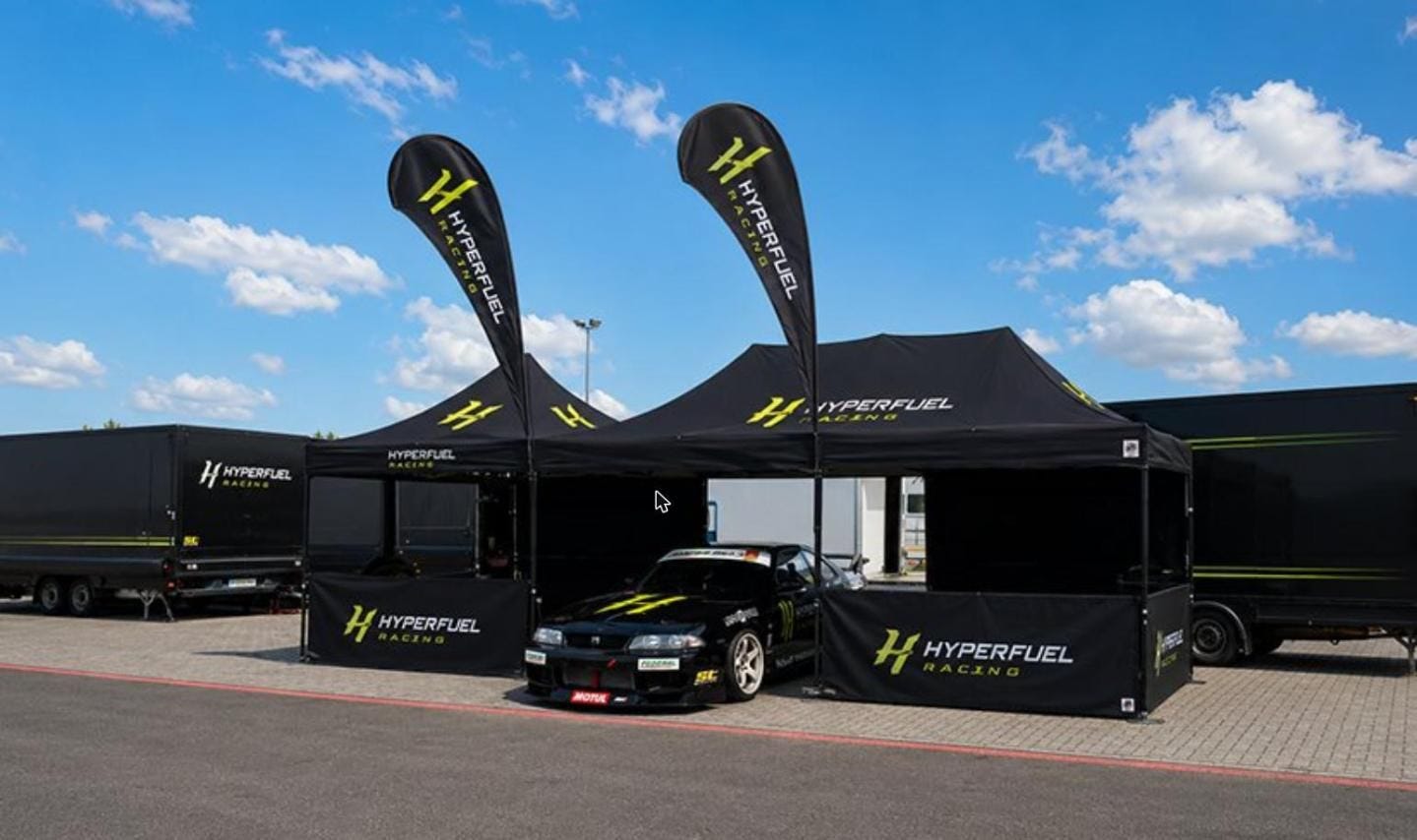 Branded canopy tent with custom logos, printed sidewalls, and feather flags at an outdoor event, showcasing effective canopy tent branding and promotional displays.